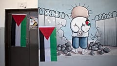 معلقة كاريكاتور للطفل الفلسطيني محمد حمايل توشح باب قسم مدرسي من بلدة بيتا في الضفة الغربية المحتلة. 