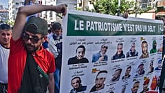 جزائريون يحملون لافتات عليها صور لنشطاء محتجزين في السجن، خلال مظاهرة مناهضة للحكومة في العاصمة الجزائر، 7 مايو 2021