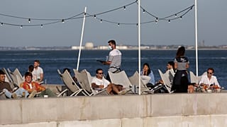 In this Friday, June 4, 2021 file photo, people have drinks by the Tagus river in Lisbon as the sun sets.