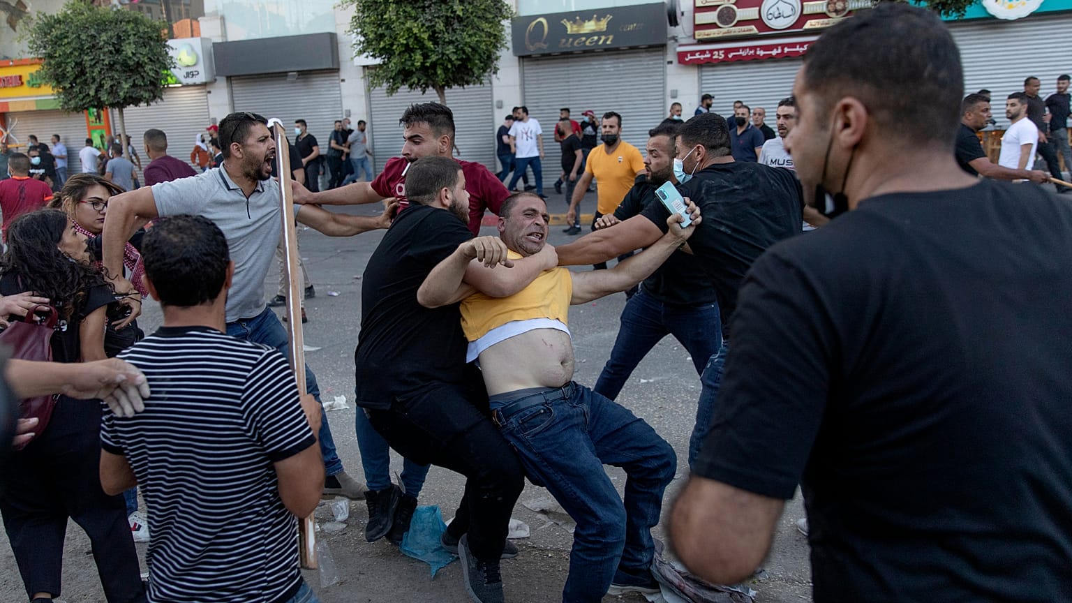 ضباط أمن فلسطينيون يرتدون ملابس مدنية يعتقلون متظاهرا خلال اشتباكات اندلعت في أعقاب مسيرة احتجاجية على مقتل الناقد الصريح للسلطة الفلسطينية نزار بنات، في رام الله.
