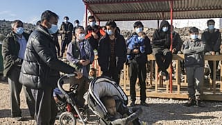 A group of migrants, wearing protective facemasks, gather outside in the new refugee camp of Kara Tepe, in the island of Lesbos, on December 19, 2020.