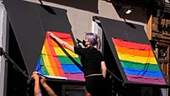 A woman hangs rainbow flags on the outside of a restaurant on the first day of the annual LGBT+ pride week in Madrid.