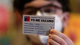 Un joven sujeta un carnet de la campaña Yo Me Vacuno