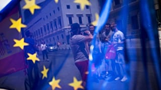 In this Friday, June 24, 2016 photo, a group of tourists posing for a photograph in front of the Spanish Parliament is seen through the EU flag in Madrid, Spain.