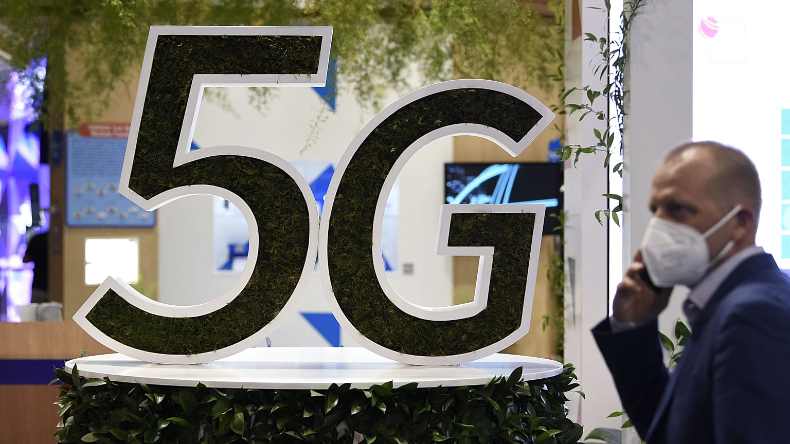 A man uses his phone next to a 5G logo at the Mobile World Congress (MWC) fair in Barcelon
