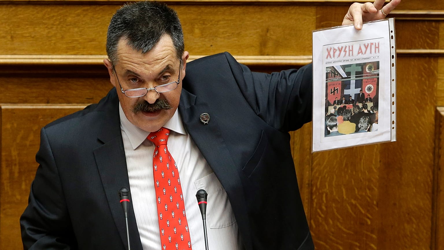 Golden Dawn's Christos Pappas shows a copy of his party magazine as he speaks to lawmakers during his time as a member of the Greek parliament, Athens, June 4, 2014.