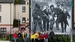 Tourists on a walking tour pass a mural depicting the 1972 Bloody Sunday killings, in the Bogside area of Derry, Northern Ireland, on March 13, 2019.