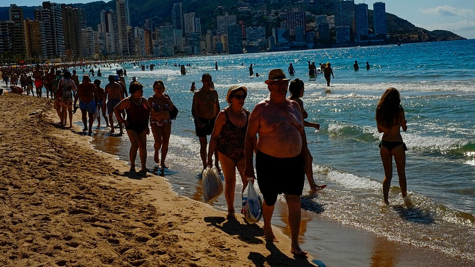  In this June 25, 2021, file photo, people walk along the beach on a summer's day in Benidorm, southeast Spain. 