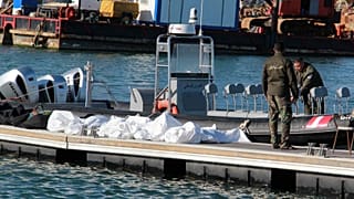 خفر السواحل التونسية يقفون بجوار جثث مهاجرين في ميناء صفاقس، وسط تونس، الخميس 24 ديسمبر 2020