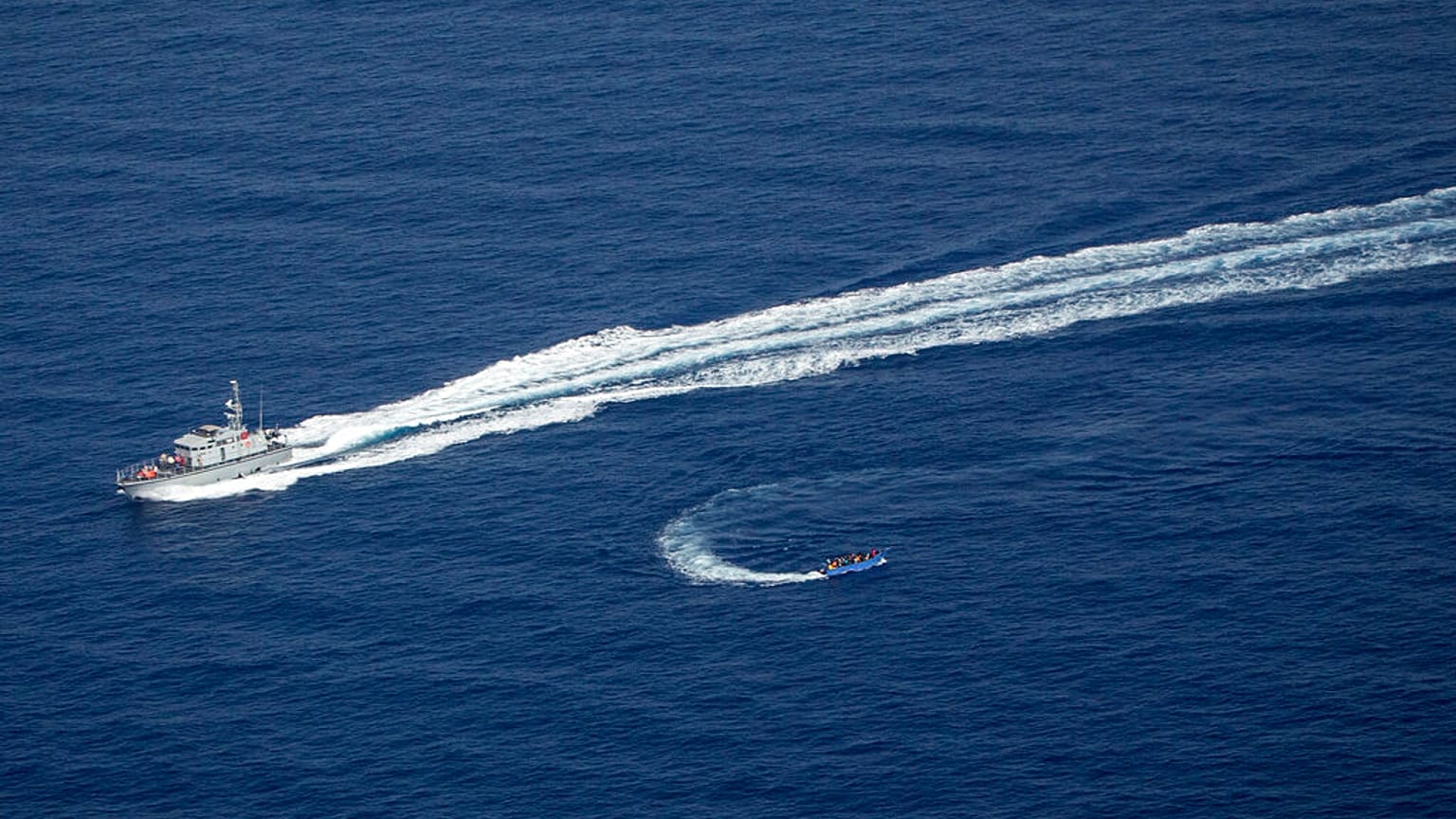 An overcrowded migrant boat, bottom, tries to escape