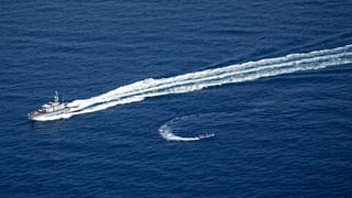 An overcrowded migrant boat, bottom, tries to escape