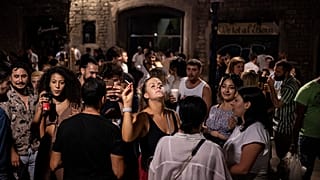 Un grupo de jóvenes está de fiesta nocturna en una concurrida calle de Barcelona.
