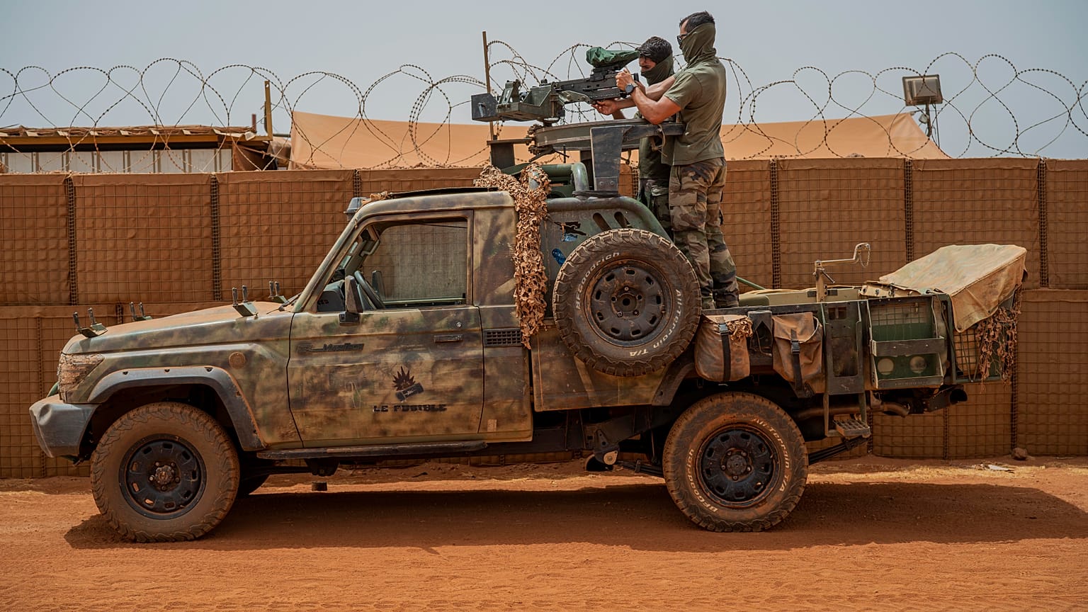 French Barkhane force commandos mount a machine gun on a camouflaged pickup as Malian workers drive by before heading on a mission from their base in Gao, Mali, June 7, 2021. 
