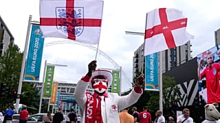 An England fan waves flags outside Wembley Stadium in London, Wednesday, July 7, 2021, ahead of the Euro 2020 soccer championship semifinal match between England and Denmark.
