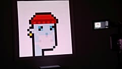 A television camera is seen next to the non-fungible token (NFT) "CryptoPunk #7523"