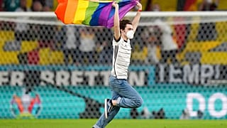 A fan with a LGBT pride flag runs on the pitch during the national anthems before the Euro 2020 soccer championship group F match between Germany and Hungary.