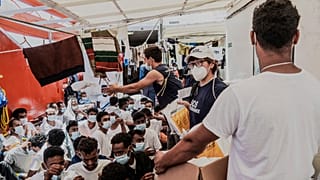 Staffers distribute food to migrants on the deck of the Ocean Viking rescue in the Mediterranean Sea