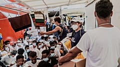 Staffers distribute food to migrants on the deck of the Ocean Viking rescue vessel.