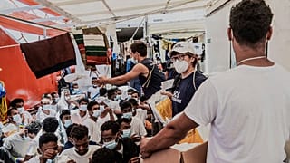 Staffers distribute food to migrants on the deck of the Ocean Viking rescue vessel.