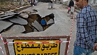 رجل يقف بجانب حفرة سببتها الأمطار الغزيرة بالعاصمة الجزائرية. 08/09/2020