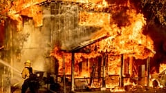A firefighter sprays water while trying to stop the Sugar Fire, part of the Beckwourth Complex Fire, from spreading to neighbouring homes in Doyle, California.
