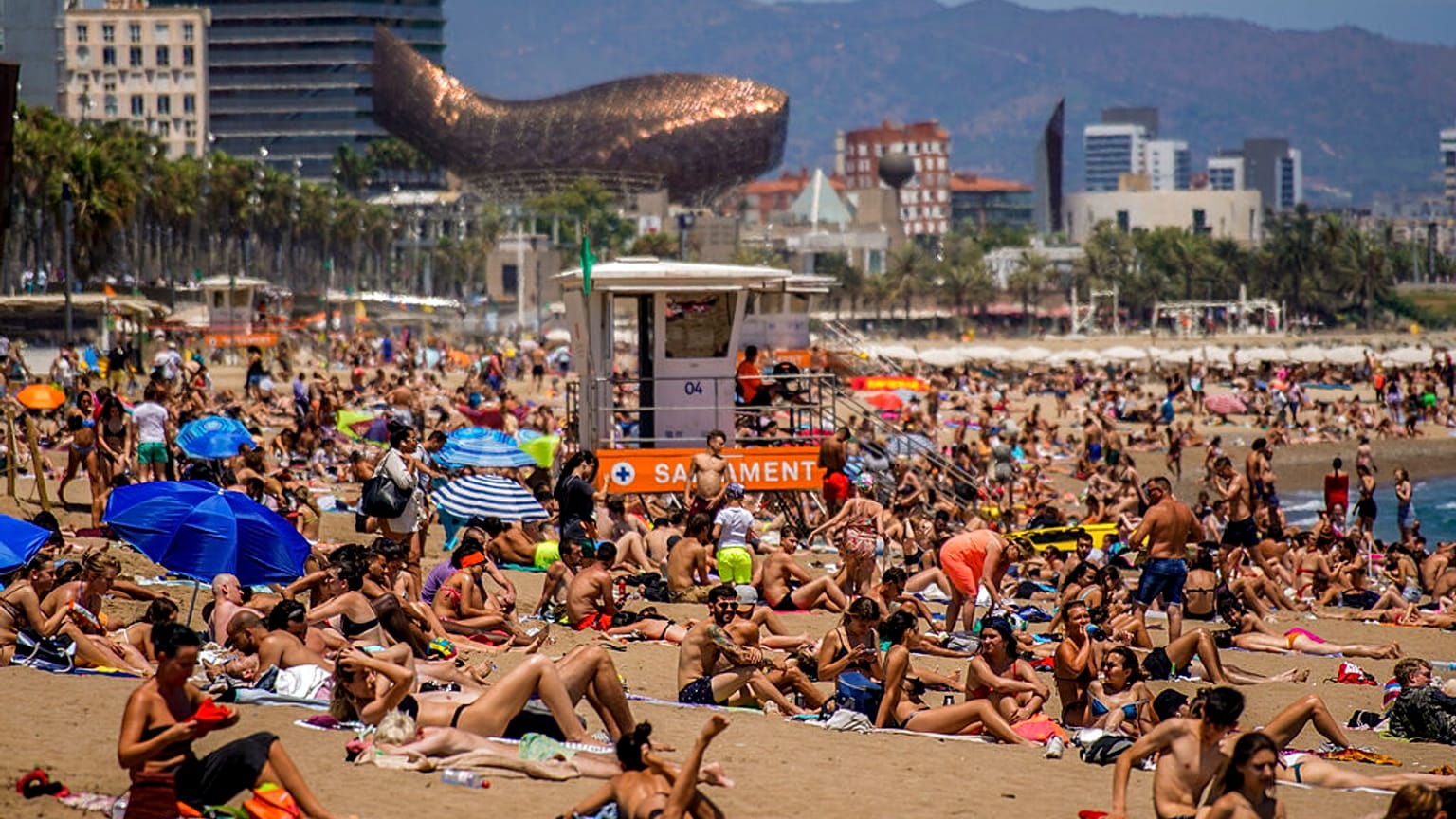Cientos de turistas se refrescan y toman el sol en una playa de Barcelona
