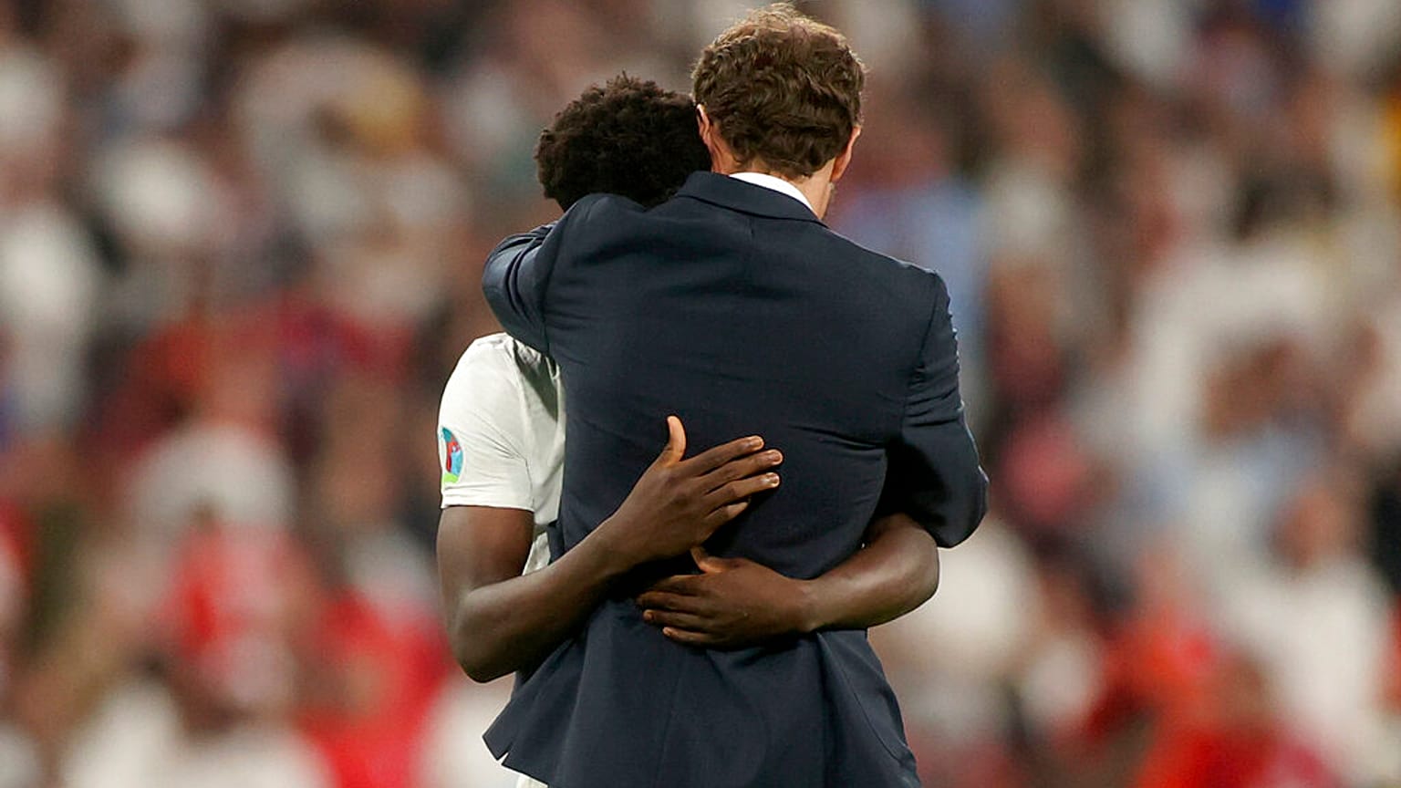 England's manager Gareth Southgate embraces Bukayo Saka after he failed to score a penalty during of the Euro 2020 final match at Wembley stadium in London,  July 11, 2021. 