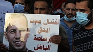 متظاهرون عراقيون يحملون لافتة تنعي الهاشمي