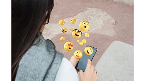 Woman using smartphone sending emojis