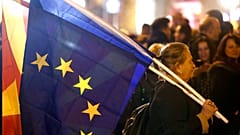 A woman holding the national and an EU flag takes a part in a rally titled "Walking for Justice," organized by the ruling Social Democrats, starting outside parliament in 2020