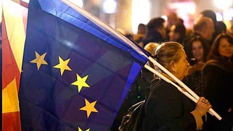A woman holding the national and an EU flag takes a part in a rally titled "Walking for Justice," organized by the ruling Social Democrats, starting outside parliament in 2020