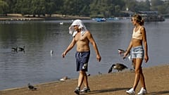 Un uomo si mantiene fresco con una maglietta sulla testa mentre cammina lungo la Serpentine in Hyde Park a Londra, 12 agosto 2020.