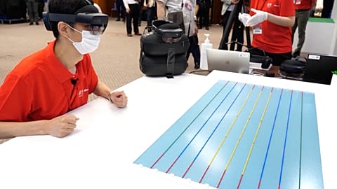 A fan uses an AR headset to observe an Olympic swimming event. 
