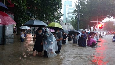 People move through flood water after a heavy downpour in Zhengzhou city, central China's Henan province on Tuesday, July 20, 2021. 