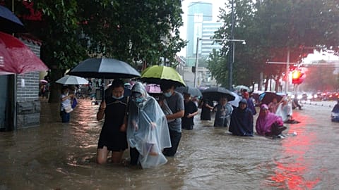 People move through flood water after a heavy downpour in Zhengzhou city, central China's Henan province on Tuesday, July 20, 2021.