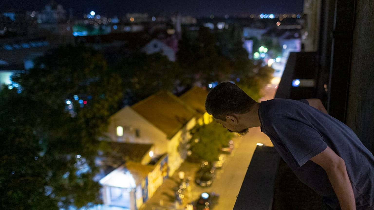Nemanja Dragic, 36, looks at a bar across the street from his balcony in Belgrade, Serbia. 