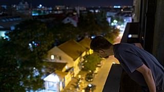 Nemanja Dragic, 36, looks at a bar across the street from his balcony in Belgrade, Serbia. 