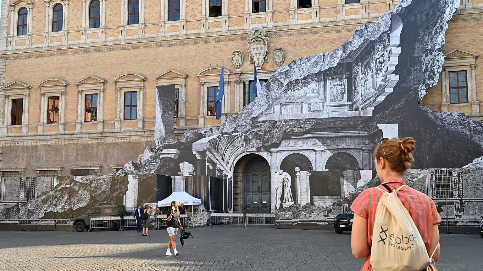 Des passants regardent l'oeuvre de JR sur la façade du palais Farnese à Rome