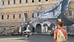 Des passants regardent l'oeuvre de JR sur la façade du palais Farnese à Rome