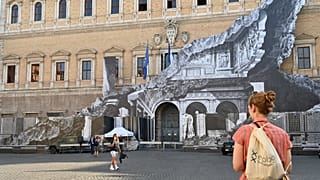 Des passants regardent l'oeuvre de JR sur la façade du palais Farnese à Rome