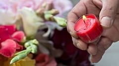 A man lights a candle beside the Olympia shopping centre in Munich.