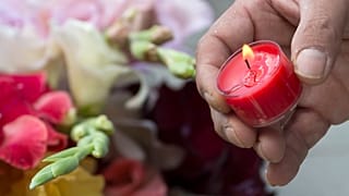 A man lights a candle beside the Olympia shopping centre in Munich.