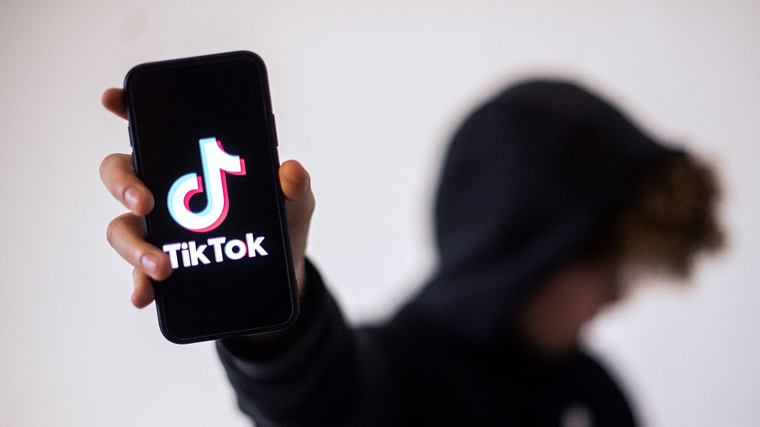 فتىً يحمل في يده جهاز موبايل على شاشته يظهر شعار تطبيق "تيك توك"