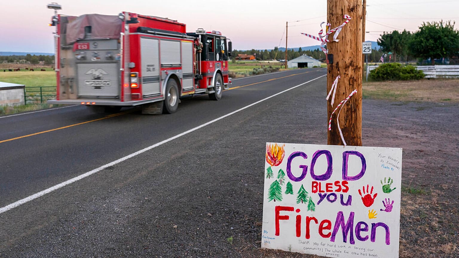 A firetruck responding to the Bootleg Fire is driven past a hand-painted sign thanking firefighters 