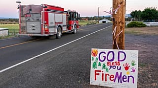 A firetruck responding to the Bootleg Fire is driven past a hand-painted sign thanking firefighters