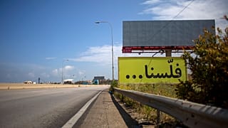 لافتة مكتوب عليها "فلسنا" على طريق سريع رئيسي فارغ، يربط بيروت بمدينة طرابلس، لبنان.