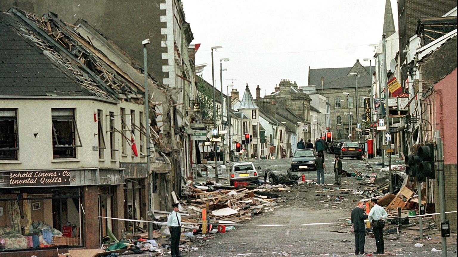 Royal Ulster Constabulary Police officers stand on Market Street at the scene of a car bombing.