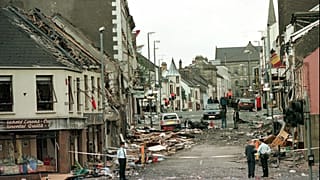 Royal Ulster Constabulary Police officers stand on Market Street at the scene of a car bombing.