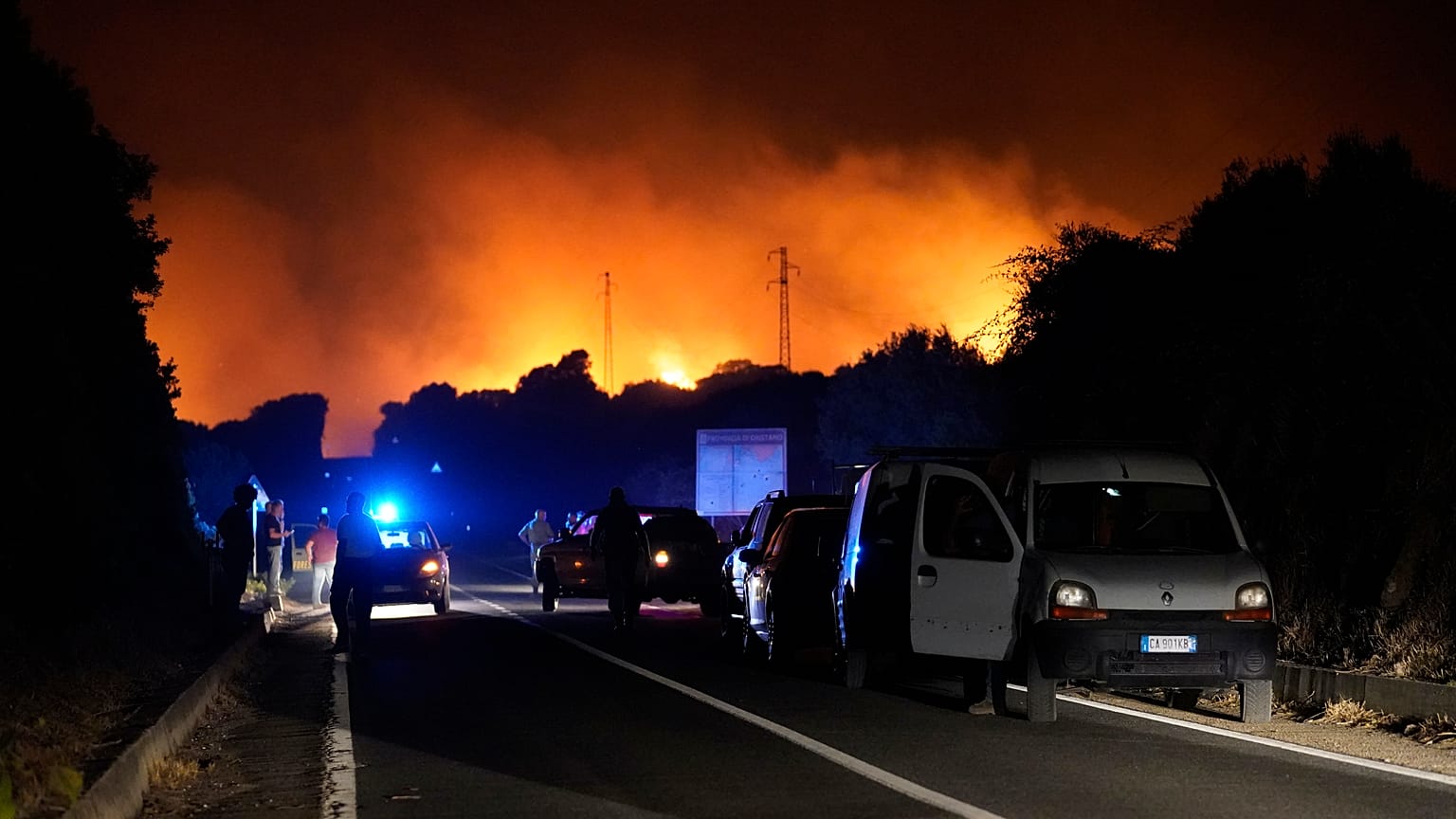 Cars are parked by the road as fires have been raging through the countryside in Cuglieri, near Oristano, Sardinia, Italy, July 25, 2021. 