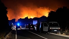 Cars are parked by the road as fires have been raging through the countryside in Cuglieri, near Oristano, Sardinia, Italy, July 25, 2021. 